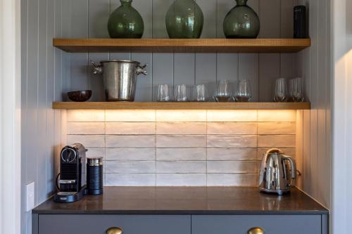 a kitchen with a counter with glasses on shelves at Smiths Cottage - Stay Waiheke in Oneroa