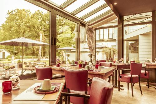 a dining room with tables and chairs and a large window at Charmehotel Klokkenhof in Brasschaat