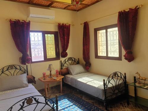 1 dormitorio con 2 camas y 2 ventanas en Maison AFA, en Tafraoute