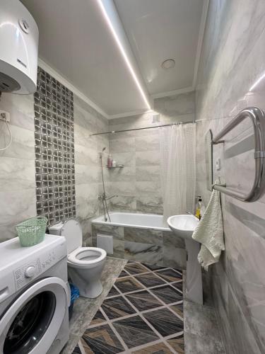 a bathroom with a toilet and a sink and a washing machine at 1-room apartment Masaka in Bishkek