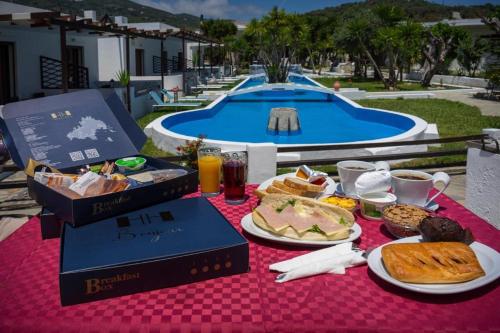 una mesa con desayuno y bebidas y una piscina en Skiathos Holiday Resort en Skiathos