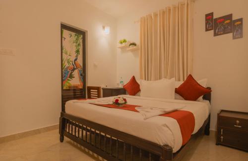 una camera da letto con un grande letto con cuscini arancioni e bianchi di Kochi Vibes Homestay a Cochin