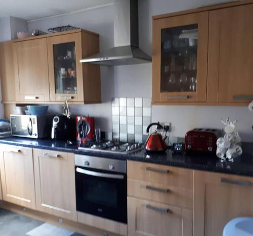 uma cozinha com armários de madeira e um forno com placa de fogão em Cosy 2 bedroom house on the edge of Balloch em Balloch
