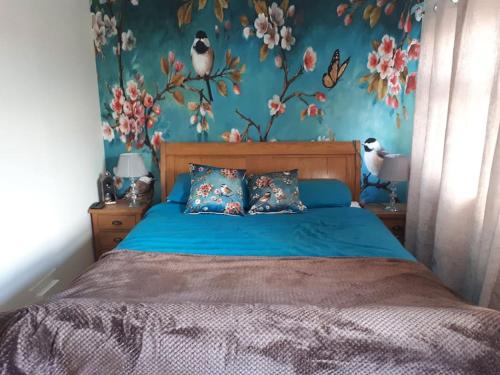 a bedroom with a blue bed with birds on the wall at Cosy 2 bedroom house on the edge of Balloch in Balloch