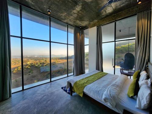 Schlafzimmer mit großen Fenstern und einem Bett mit Aussicht in der Unterkunft Wabi Sabi Resort, Igatpuri in Wādhiware