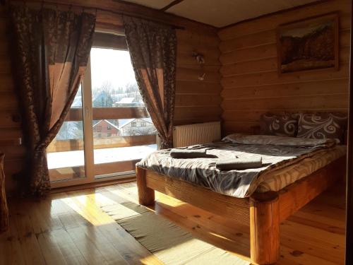 a bedroom with a bed and a large window at Sadyba Cherry in Pilipets