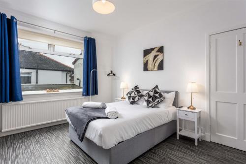 a bedroom with a bed with blue curtains and a window at Berelands House - Donnini Apartments in Prestwick