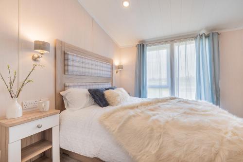 1 dormitorio con cama blanca y ventana en Birch Timber Holiday Lodge, en Bassenthwaite