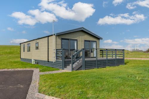 a small house in a field with a grassy field at Birch Timber Holiday Lodge in Bassenthwaite