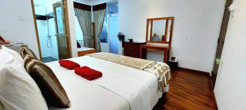 a bedroom with a white bed with red pillows on it at Poomaz Peace Palace in Ella