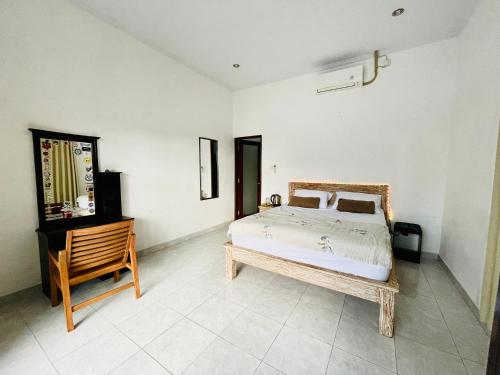 una camera con letto e sedia in legno di NAMA Guest House a Canggu