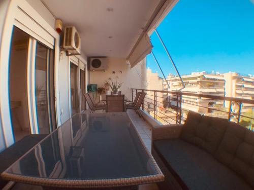 einen Balkon mit einem Sofa und einem Tisch auf einem Gebäude in der Unterkunft Acropolis view Luxury 2-bedroom Condo in Athen