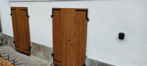 two wooden doors on the side of a wall at alloggio in centro con giardino in Sampeire