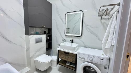 La salle de bains est pourvue d'un lavabo et d'un lave-linge. dans l'établissement 2х комнатные апартаменты 12-106, à Almaty