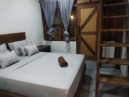 a bedroom with a white bed and a book shelf at Asoka Homestay in Senggigi