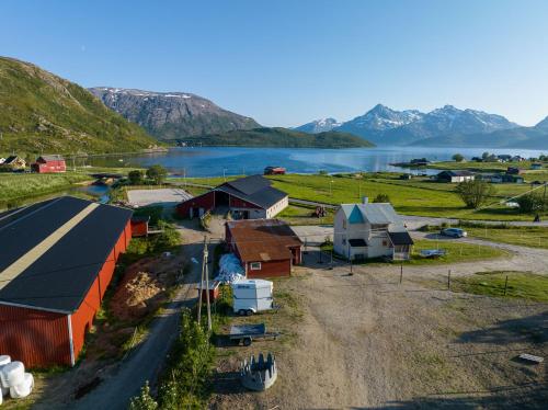 Storjord Farmstay Ranchhouse في Kvaløya: اطلالة جوية على مزرعة فيها بحيرة وجبال