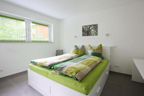 Un dormitorio con una cama verde en una habitación blanca en Moderne 3-Zimmerwohnung Rottweil Zentrum en Rottweil