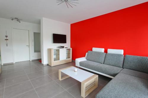 a living room with a couch and a red wall at Moderne 3-Zimmerwohnung Rottweil Zentrum in Rottweil