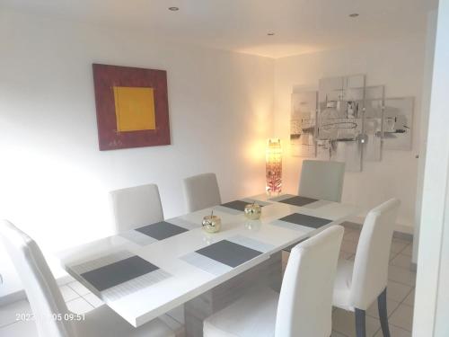 une salle à manger avec une table blanche et des chaises blanches dans l'établissement Maison familiale charmante à Andonville avec jardin, à Andonville