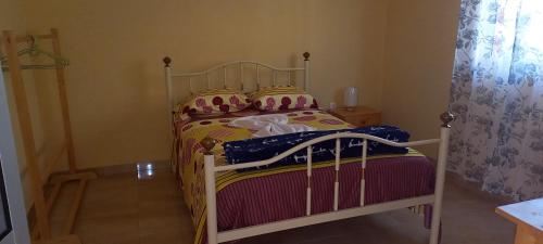 a small bedroom with a bed with colorful sheets and pillows at Casa Adriano & Filomena Montrond in Portela