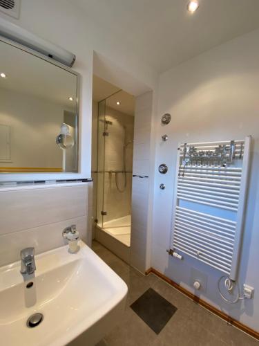 ein weißes Bad mit einem Waschbecken und einer Dusche in der Unterkunft Ferienwohnungen Ostsee & Mehr in Heringsdorf