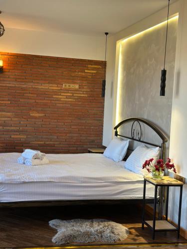 a bedroom with a large bed and a brick wall at Wine Hills in Tbilisi City