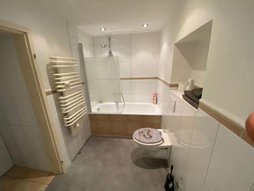a white bathroom with a toilet and a bath tub at Ferien-Villa direkt am Rhein Sauna/Whirlpool in Götterswickerhamm