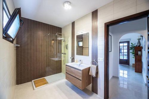 ein Bad mit einem Waschbecken und einer Dusche sowie einen TV in der Unterkunft Casa de la Luna in Tías