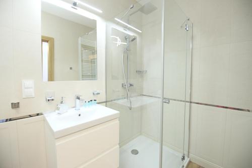 a white bathroom with a sink and a shower at Apartimento Angel River 7 in Wrocław