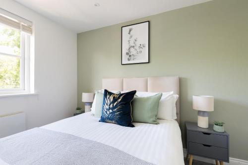 a bedroom with a white bed with blue pillows at The West Brompton Collection in London