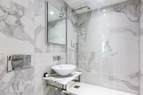 a white bathroom with a sink and a shower at The West Brompton Collection in London
