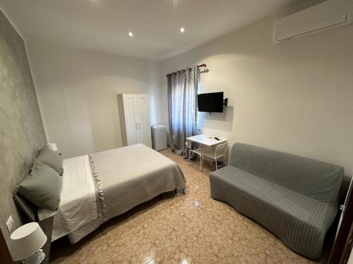 a bedroom with a bed and a couch and a desk at Mondo House in Fiumicino