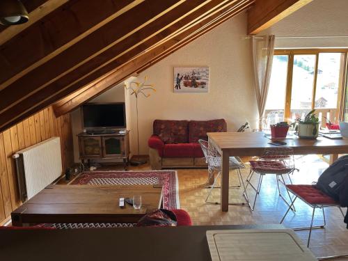 ein Wohnzimmer mit einem Tisch und einem Sofa in der Unterkunft Chalet Les Rhodos appartement le Yeti in Les Crosets