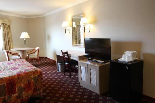 une chambre d'hôtel avec un lit, un bureau et une table dans l'établissement Metro Plaza Hotel, à Los Angeles