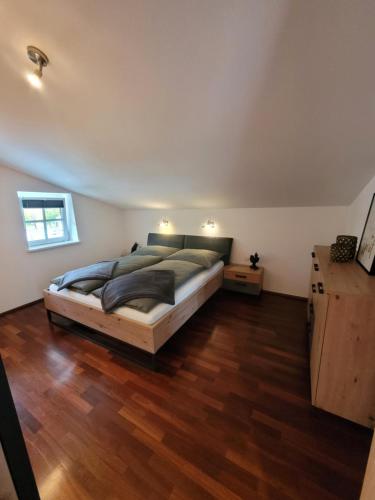 een slaapkamer met een groot bed en een houten vloer bij Appartement Lockei in Eben im Pongau