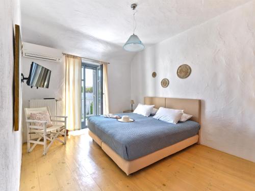 a bedroom with a bed and a chair in it at Amelie Villa with pool and amazing sea views, Paros in Márpissa