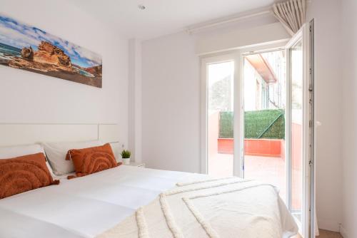 a white bedroom with a bed and a large window at Moderno y cómodo apartamento en calle Vargas in Santander