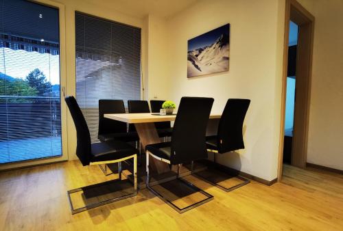 uma sala de jantar com uma mesa e cadeiras pretas em Alpenblume em Imst
