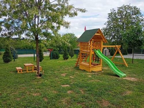 un parco giochi con scivolo e una casetta per i giochi di Fruskogorske brvnare a Velika Remeta