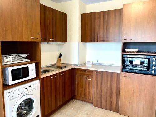 a kitchen with wooden cabinets and a washer and dryer at Private Suite at Comfort Bansko in Bansko