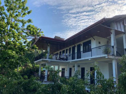 a white house with a balcony and trees at Hotel Siyathma polonnaruwa in Polonnaruwa