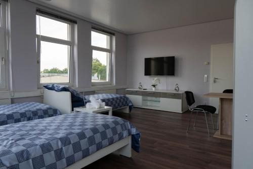 a hotel room with two beds and a flat screen tv at SKY Apartments Hannover in Hannover