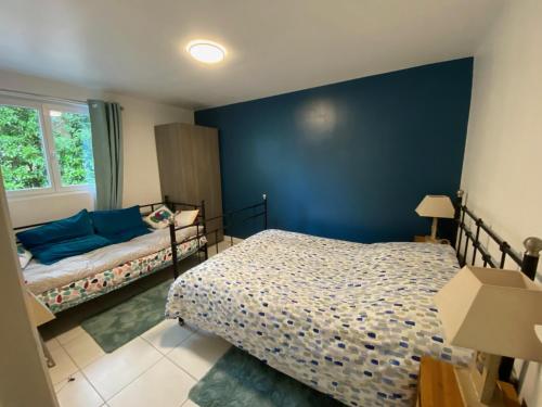 1 dormitorio con cama y pared azul en Maison dans parc privé, sports et loisirs proche golf du Coudray Montceaux, en Le Coudray-Montceaux