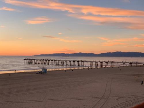 - une vue sur une plage avec une jetée au coucher du soleil dans l'établissement The Vurpillat, à Hermosa Beach