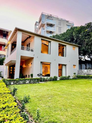 a white house with a green lawn in front of it at Yog Niketan Villa in Rishīkesh