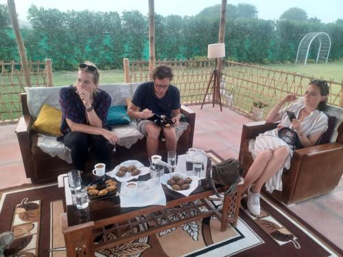 a group of three people sitting on a couch at TENTFORTABLE Village Retreat in Agra