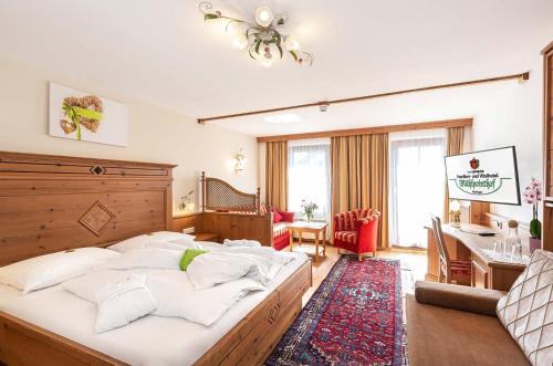 a bedroom with a large bed and a desk at Familien- und Vitalhotel Mühlpointhof in Lofer
