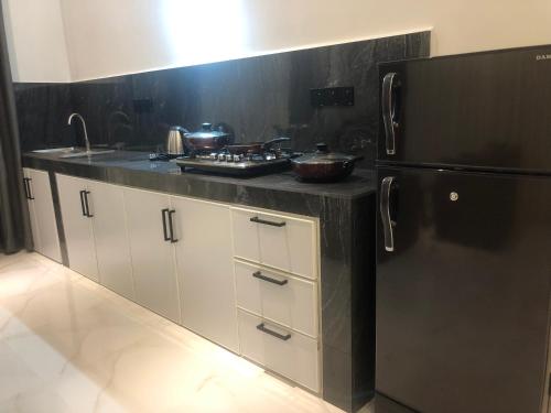 a kitchen with a black refrigerator and white cabinets at Luvi’s Villa in Galle