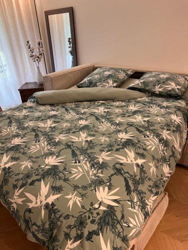 a bed with a green and white comforter at La perle du parc - Studio in Rocquencourt
