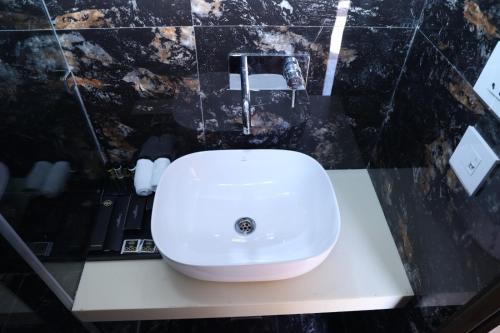a white sink in a bathroom with a black wall at THE FORT in Morādābād